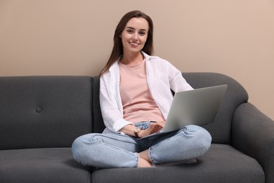 Smiling woman with laptop on sofa at home