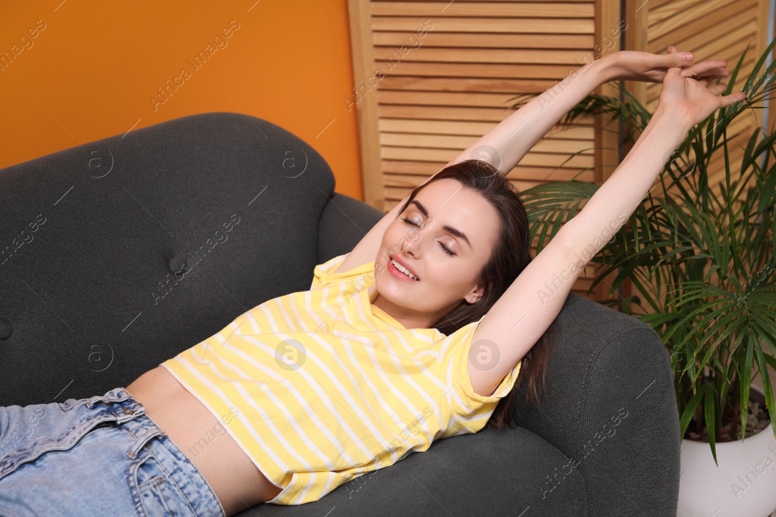 Photo of Smiling woman stretching on sofa at home