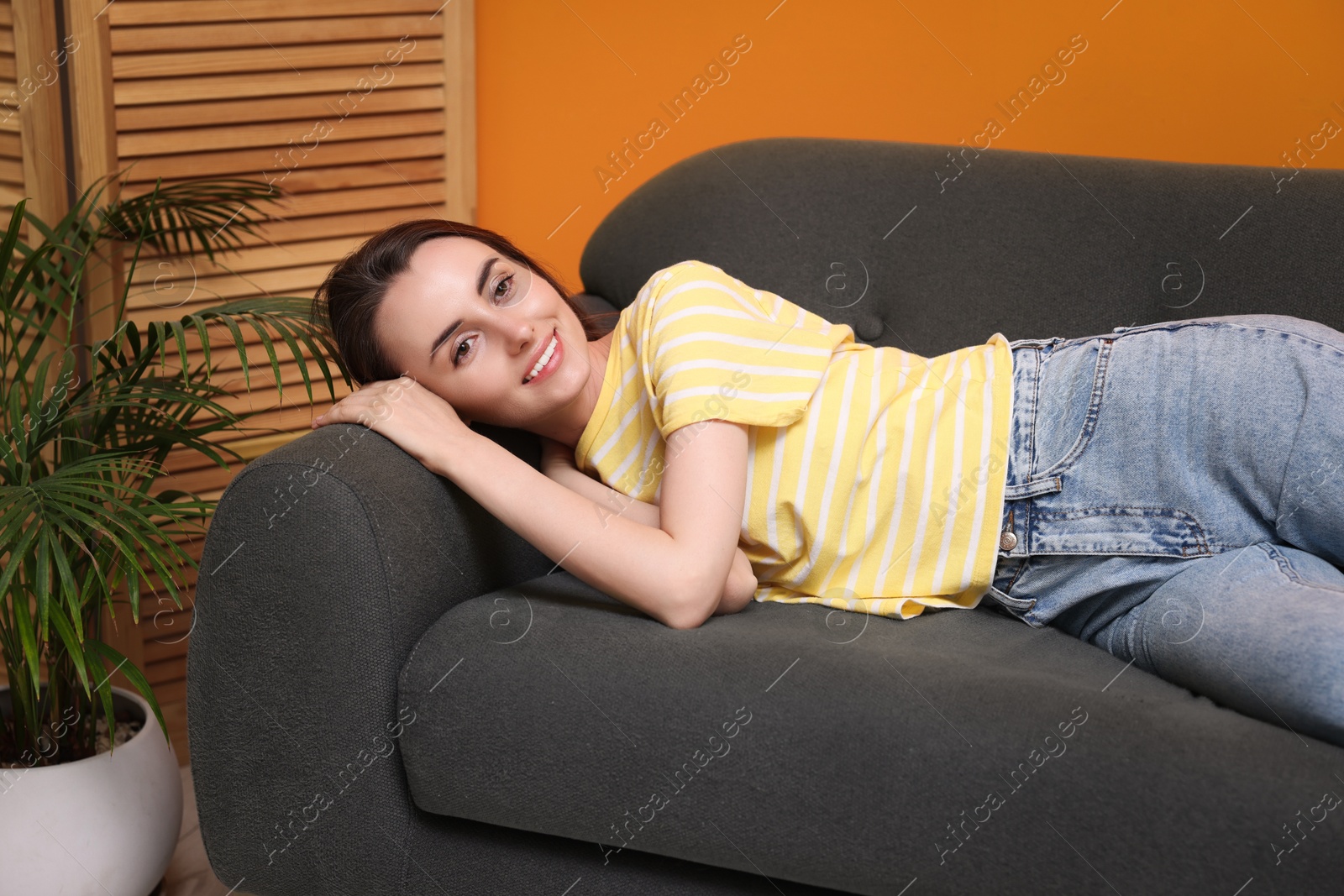 Photo of Smiling woman relaxing on sofa at home