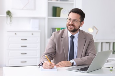 Photo of Smiling businessman working at table in office. Space for text