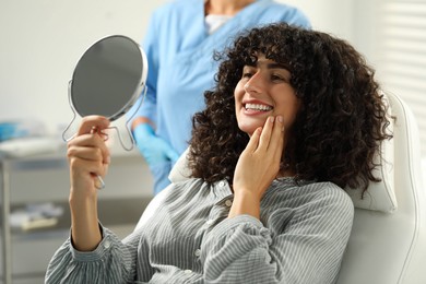 Patient looking in mirror and doctor in clinic, selective focus. Dental veneers