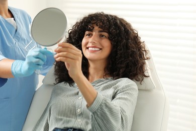 Photo of Patient looking in mirror and doctor in clinic. Dental veneers