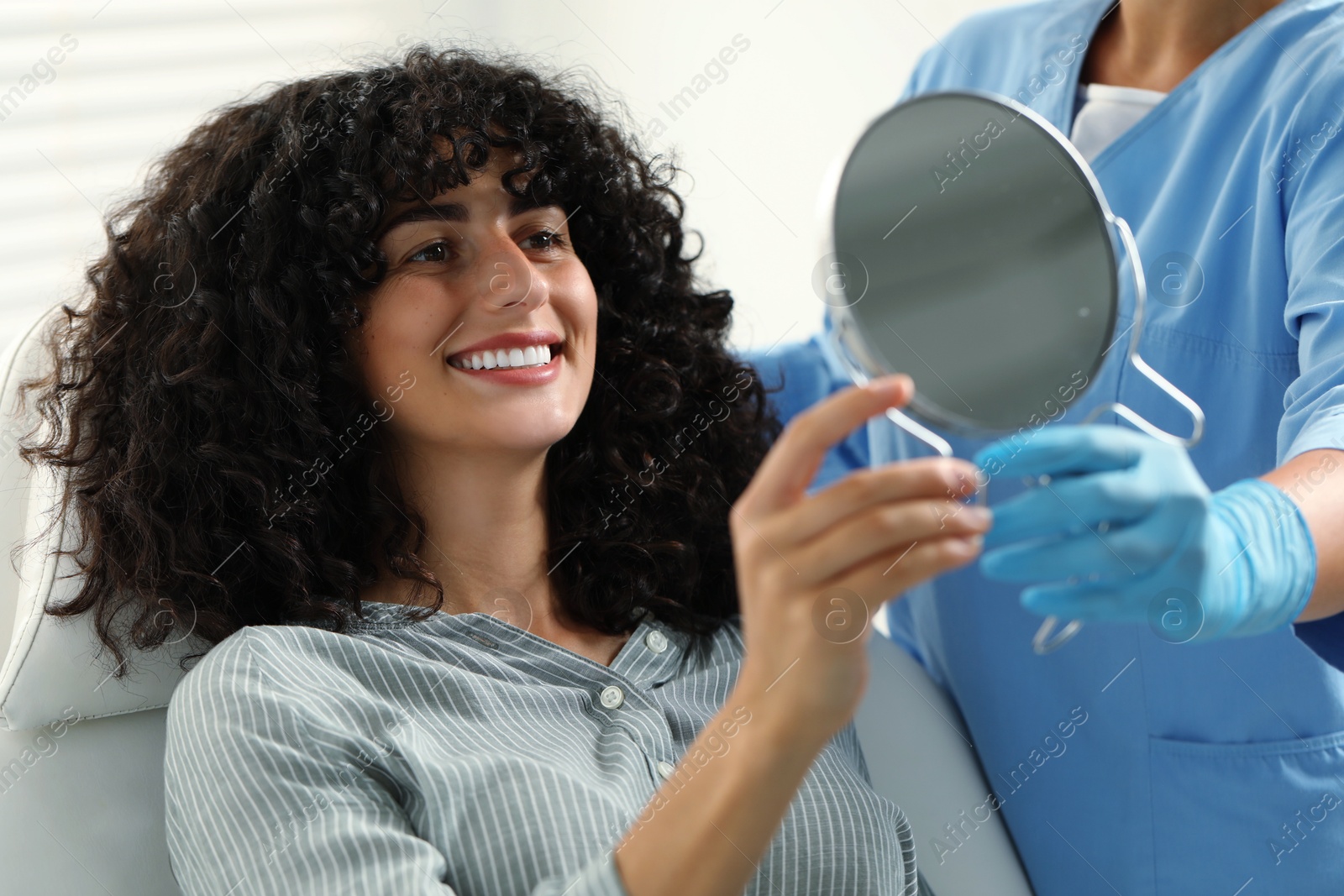 Photo of Patient looking in mirror and doctor in clinic. Dental veneers