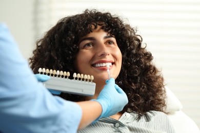 Photo of Doctor checking young woman's teeth color in clinic, closeup. Dental veneers