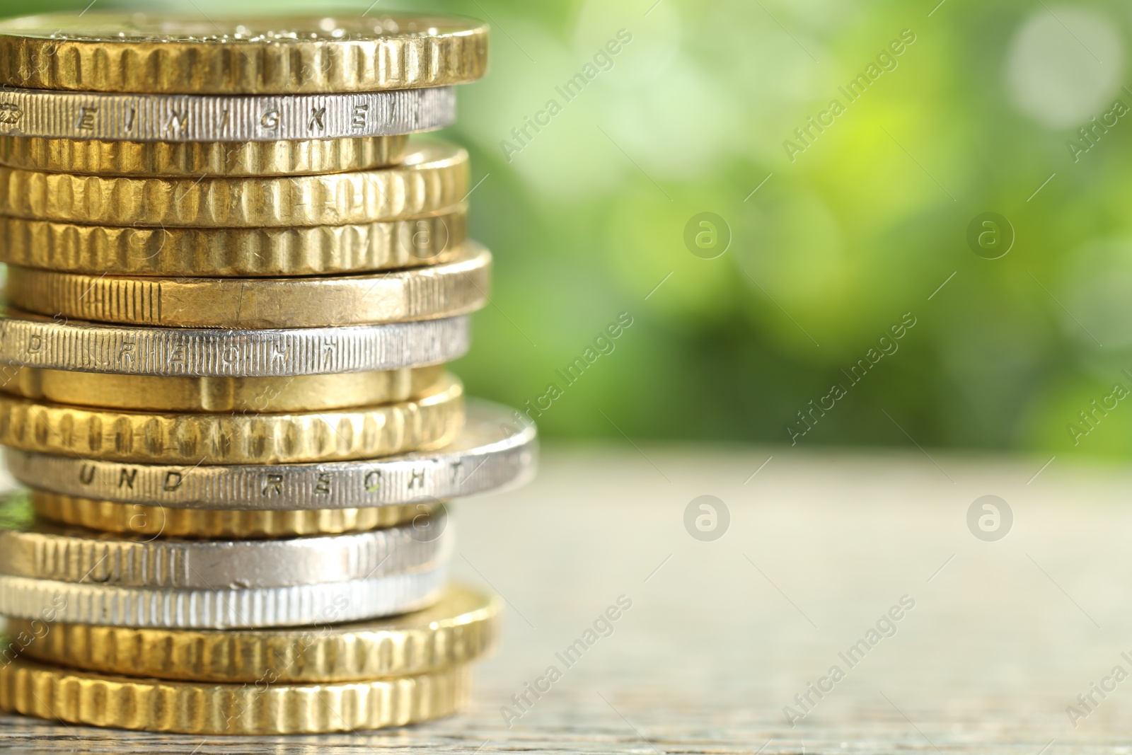 Photo of Salary concept. Stacked coins on grey table against blurred background, closeup. Space for text