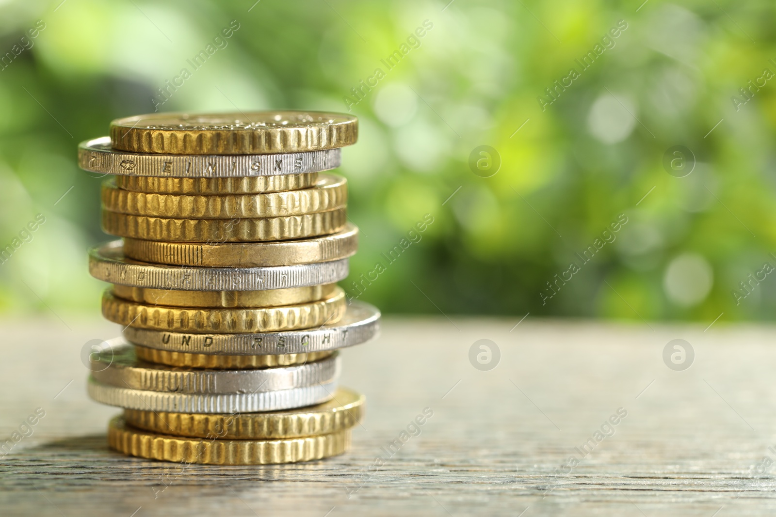 Photo of Salary concept. Stacked coins on grey table against blurred background, closeup. Space for text