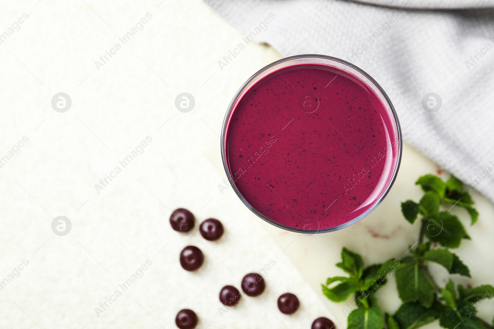 Photo of Tasty fresh acai juice in glass on light table, top view. Space for text