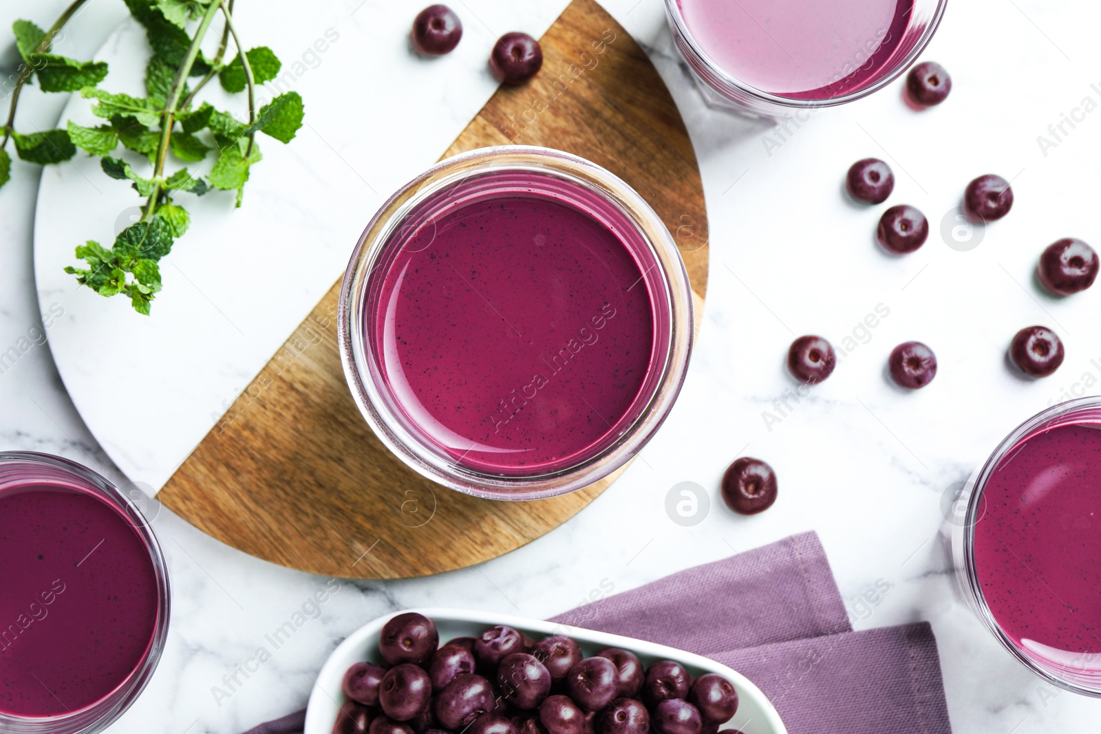 Photo of Tasty fresh acai juice in glasses, mint and berries on white marble table, flat lay