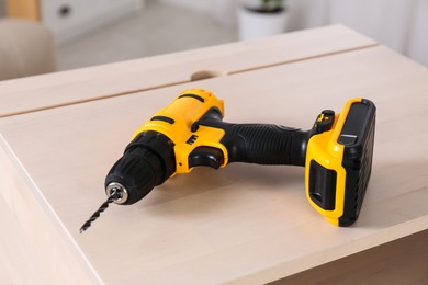 Cordless electric screwdriver on wooden table at home