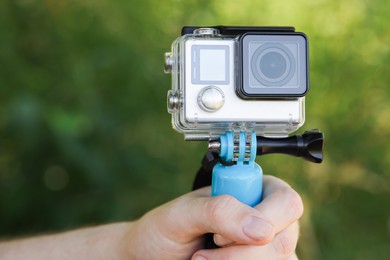 Man holding monopod with modern action camera outdoors, closeup