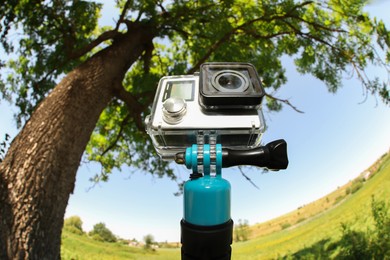 Modern action camera with monopod outdoors. Fisheye lens effect