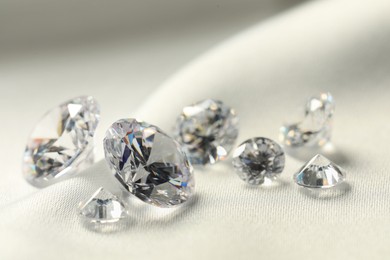 Many beautiful shiny diamonds on white fabric, closeup