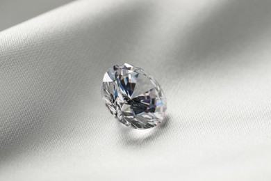 One beautiful shiny diamond on white fabric, closeup