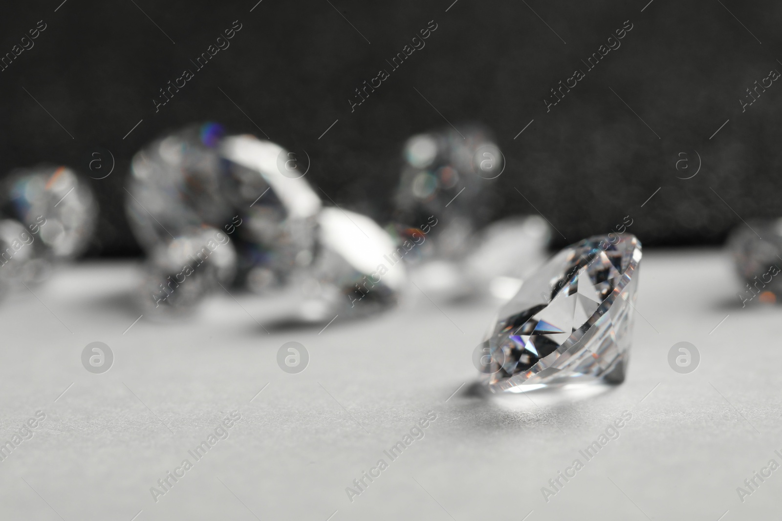 Photo of Beautiful dazzling diamonds on light grey table, closeup. Space for text