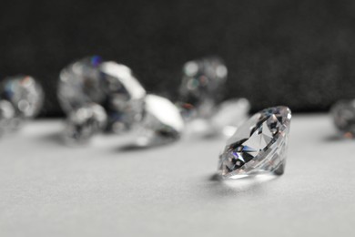 Beautiful dazzling diamonds on light grey table, closeup. Space for text