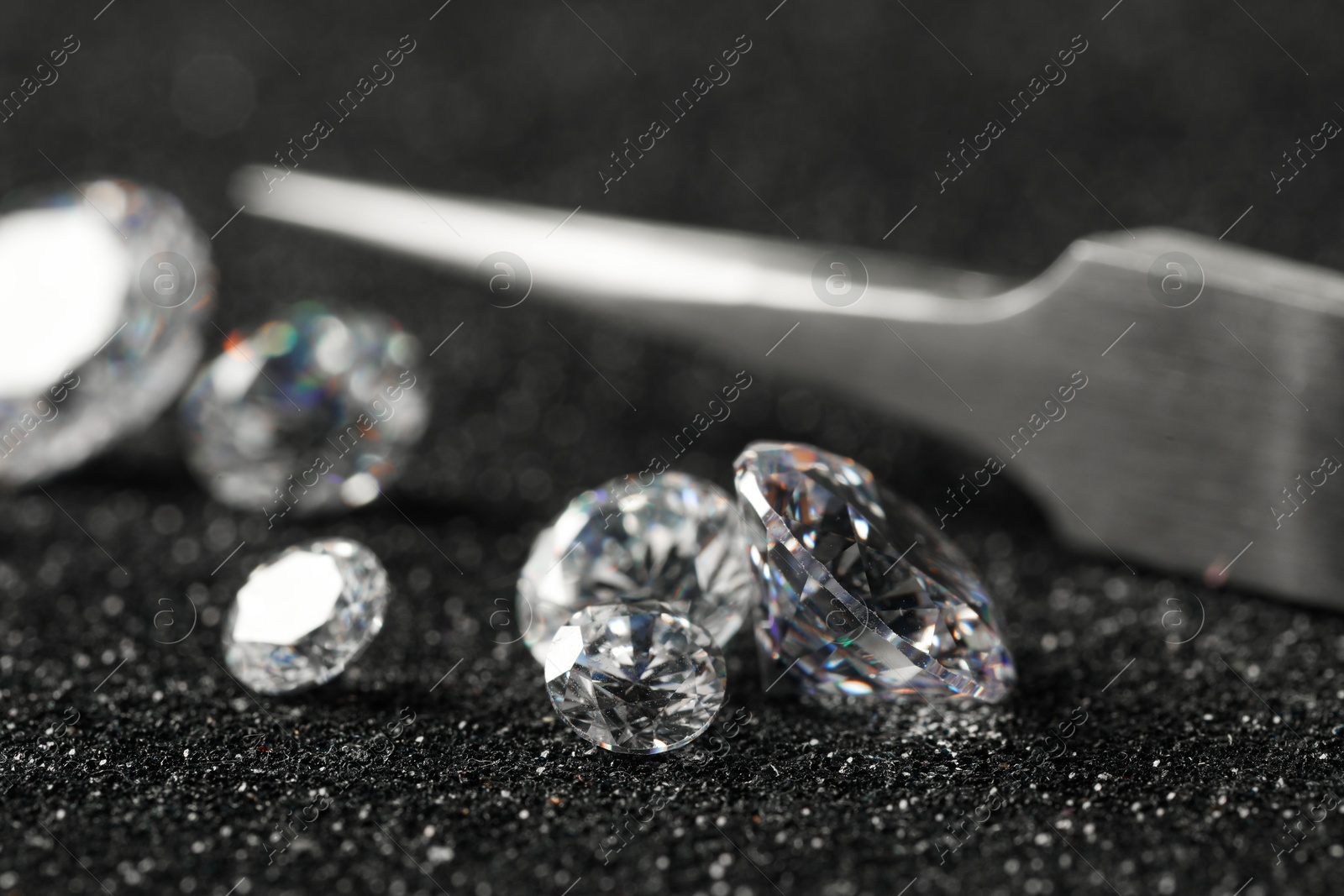 Photo of Beautiful dazzling diamonds and tweezers on dark shiny background, closeup