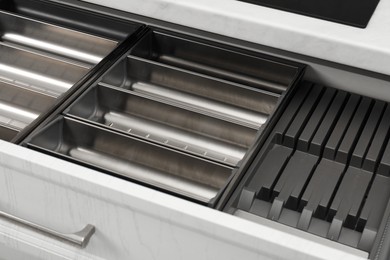 Photo of Open drawer of kitchen cabinet with space for cutlery, closeup