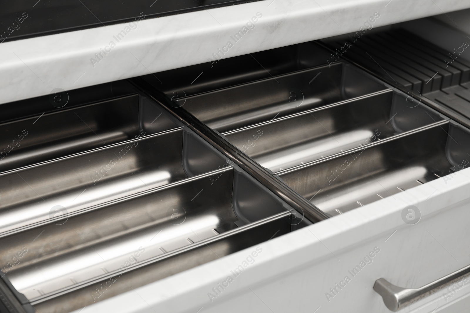 Photo of Open drawer of kitchen cabinet with space for cutlery, closeup