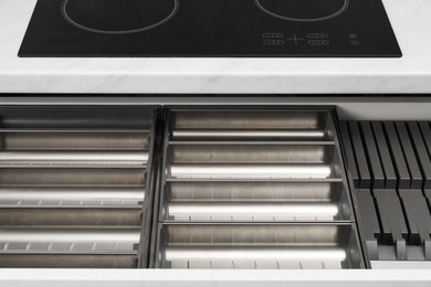 Open drawer of kitchen cabinet with space for cutlery, closeup