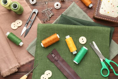 Flat lay composition with different sewing supplies on wooden table