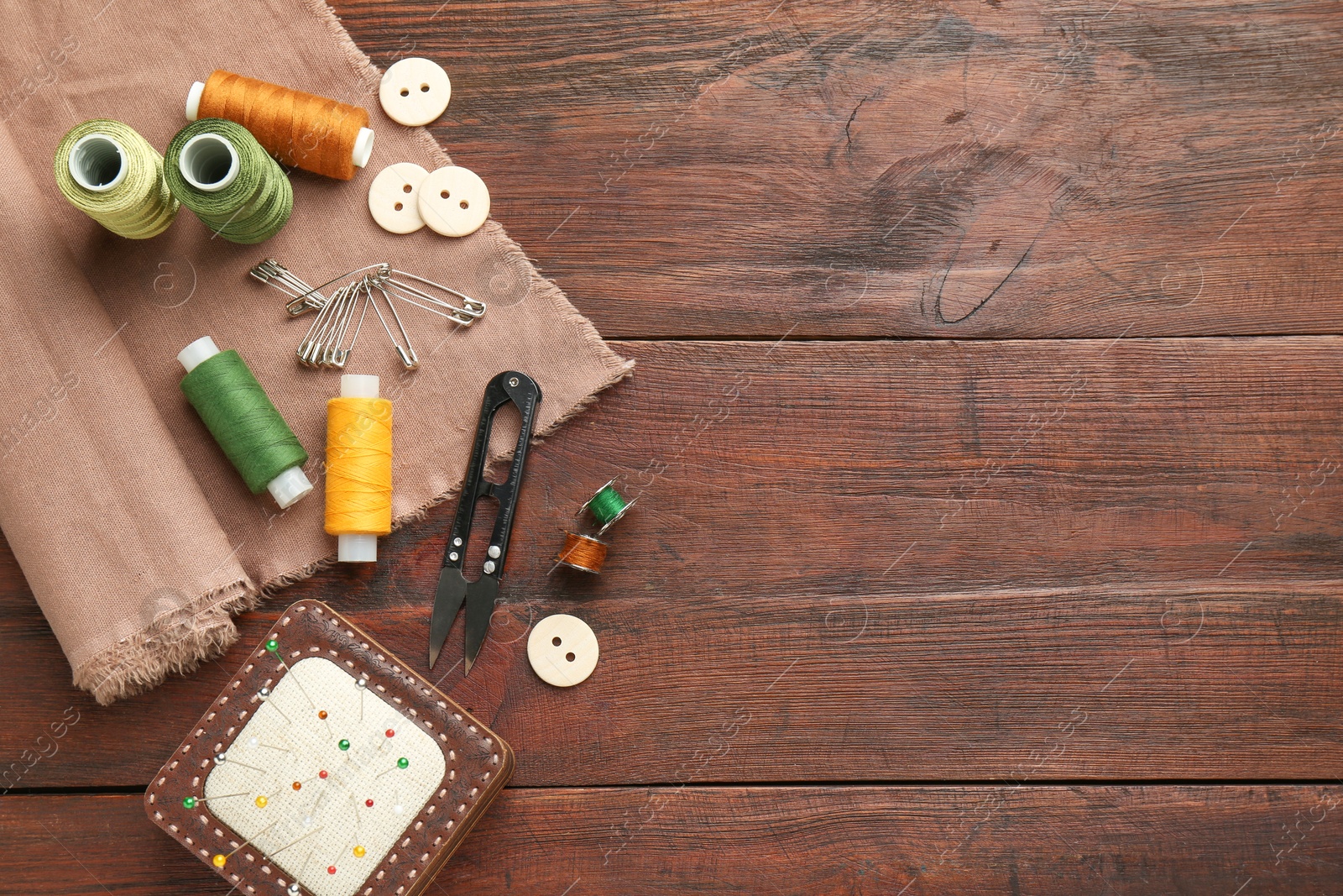 Photo of Flat lay composition with different sewing supplies on wooden table. Space for text