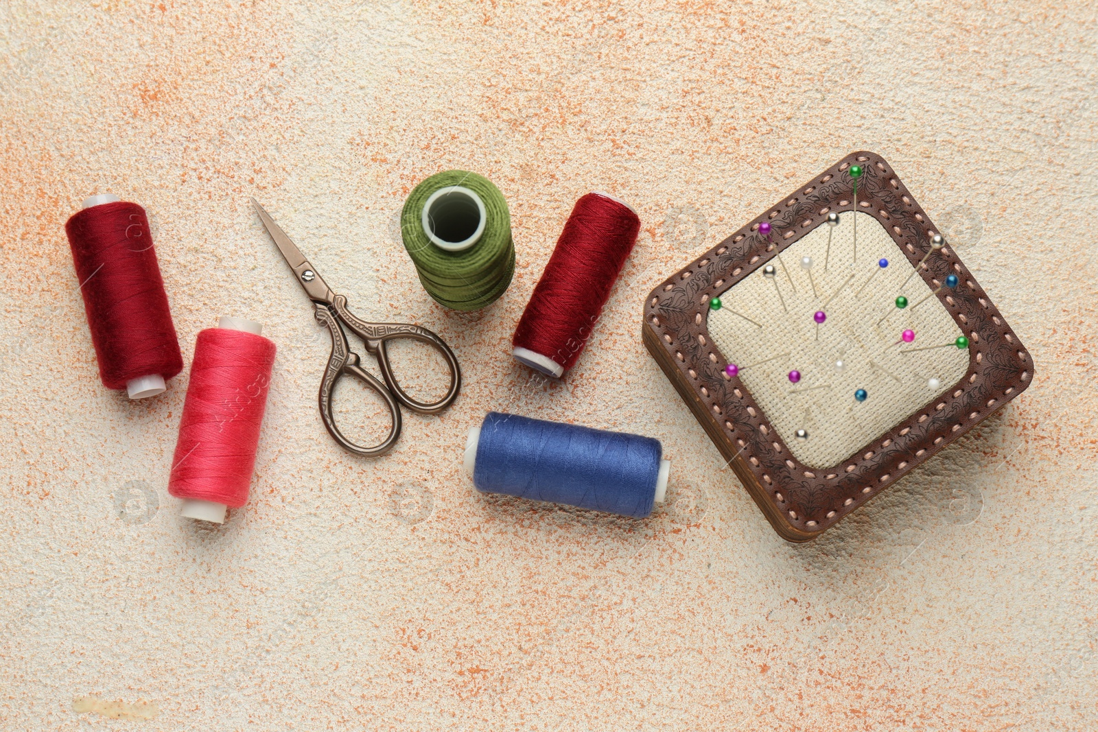 Photo of Flat lay composition with different sewing supplies on beige textured table