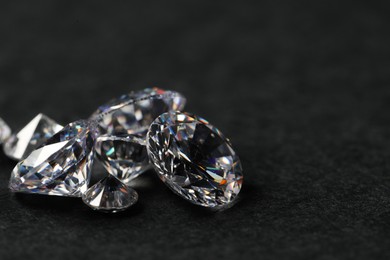 Photo of Many beautiful shiny diamonds on black table, closeup. Space for text