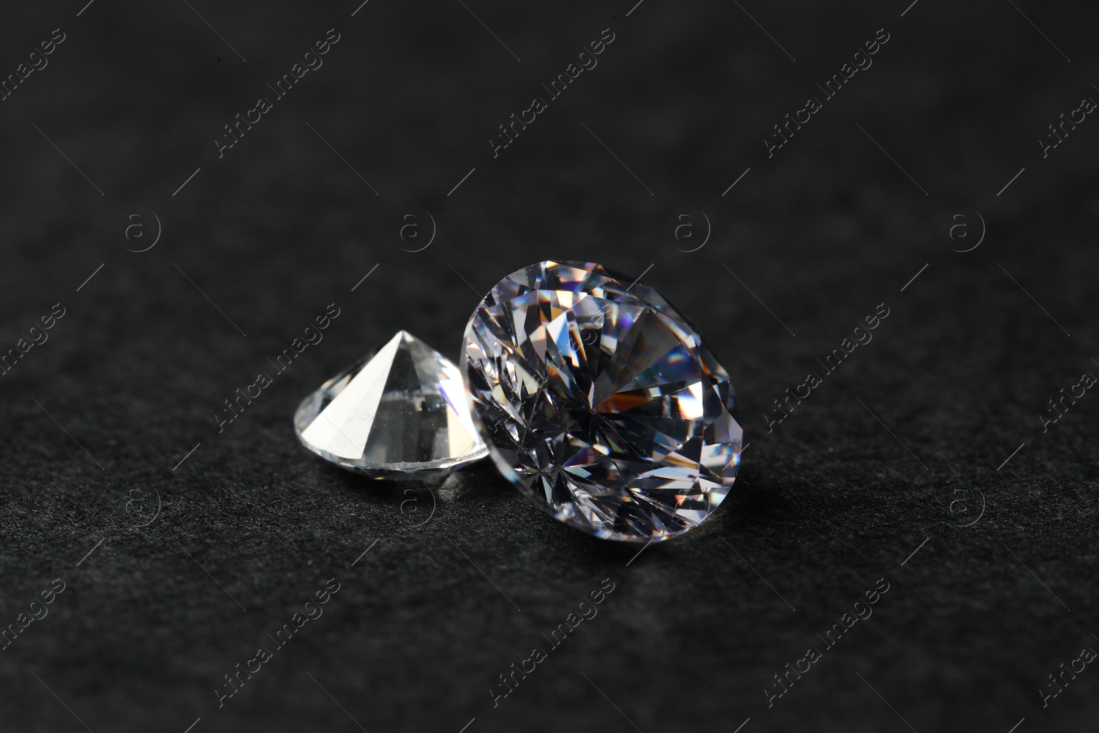 Photo of Two beautiful shiny diamond on black table, closeup