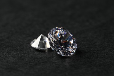 Photo of Two beautiful shiny diamond on black table, closeup