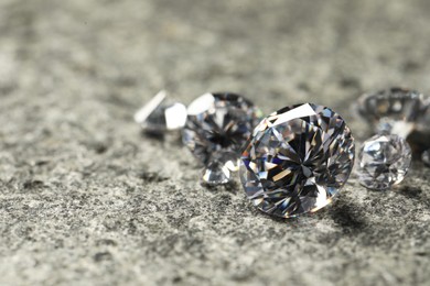 Photo of Many beautiful shiny diamonds on grey table, closeup. Space for text