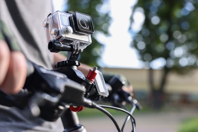 Man riding bicycle with modern action camera outdoors, closeup. Space for text