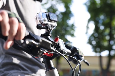 Photo of Man riding bicycle with modern action camera outdoors, closeup. Space for text