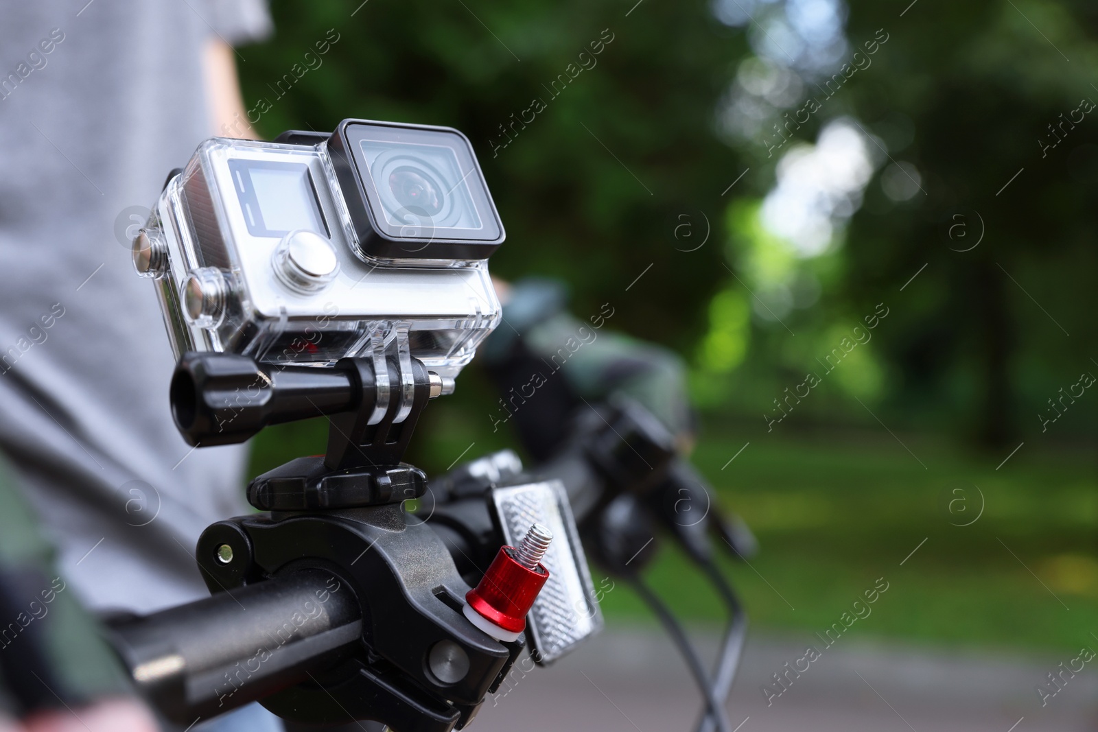 Photo of Man riding bicycle with modern action camera outdoors, closeup. Space for text