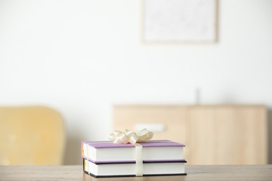 Hardcover books with ribbon as gift on wooden table indoors