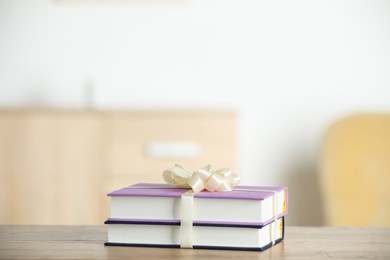 Photo of Hardcover books with ribbon as gift on wooden table indoors