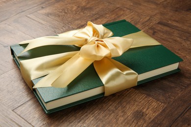 Photo of Hardcover book with ribbon as gift on wooden table