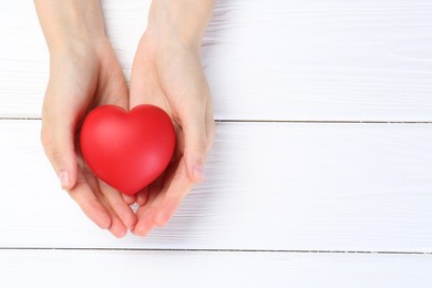 Photo of Woman holding red heart on white wooden background, top view. Space for text