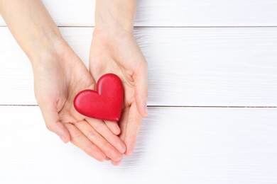 Photo of Woman holding red heart on white wooden background, top view. Space for text