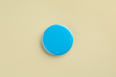 Photo of Blue button badge on beige background, top view. Mockup for design