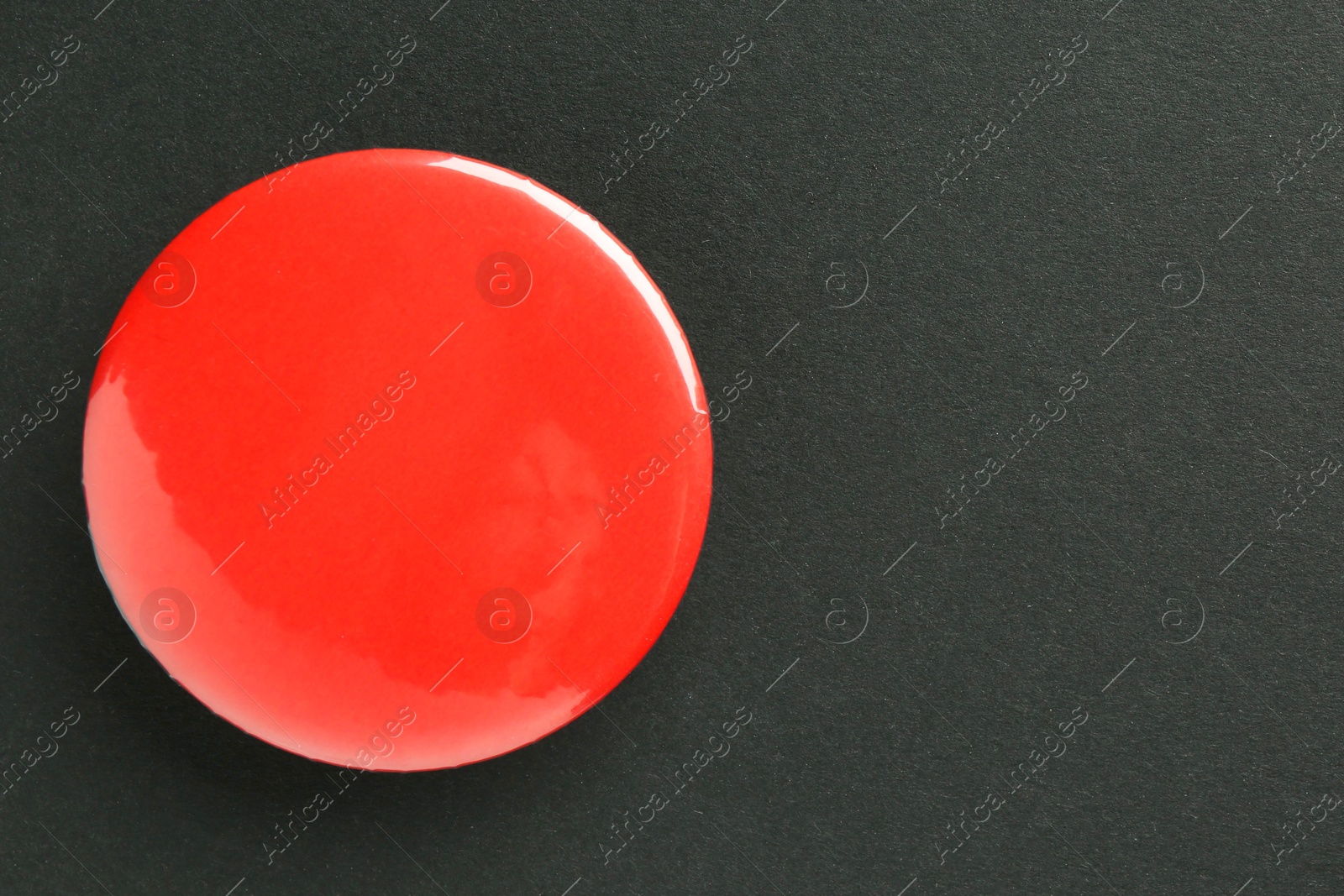 Photo of Red button badge on black background, top view. Mockup for design