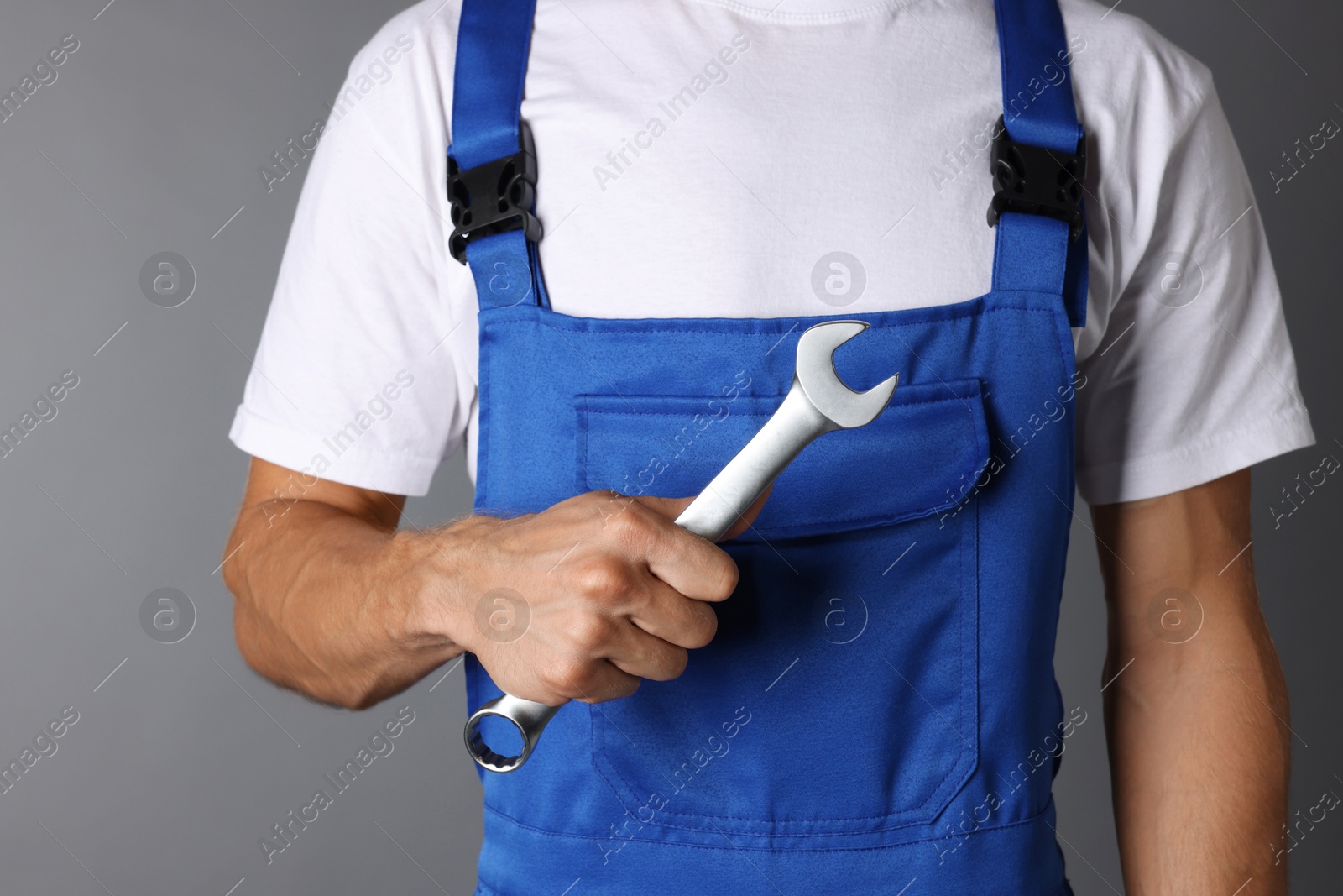 Photo of Auto mechanic with wrench on grey background, closeup