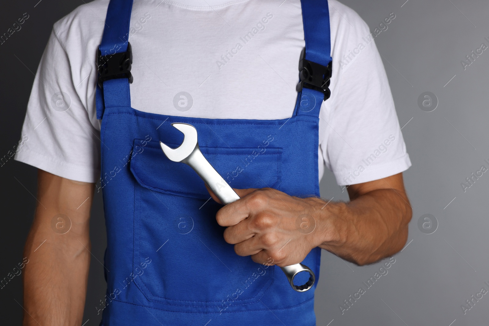 Photo of Auto mechanic with wrench on grey background, closeup