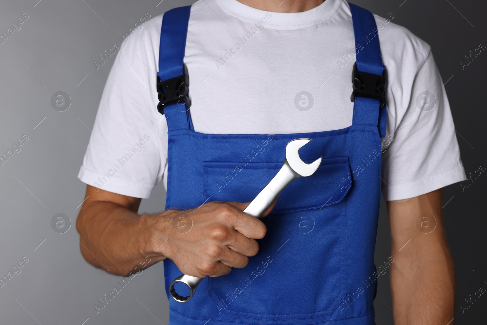 Photo of Auto mechanic with wrench on grey background, closeup