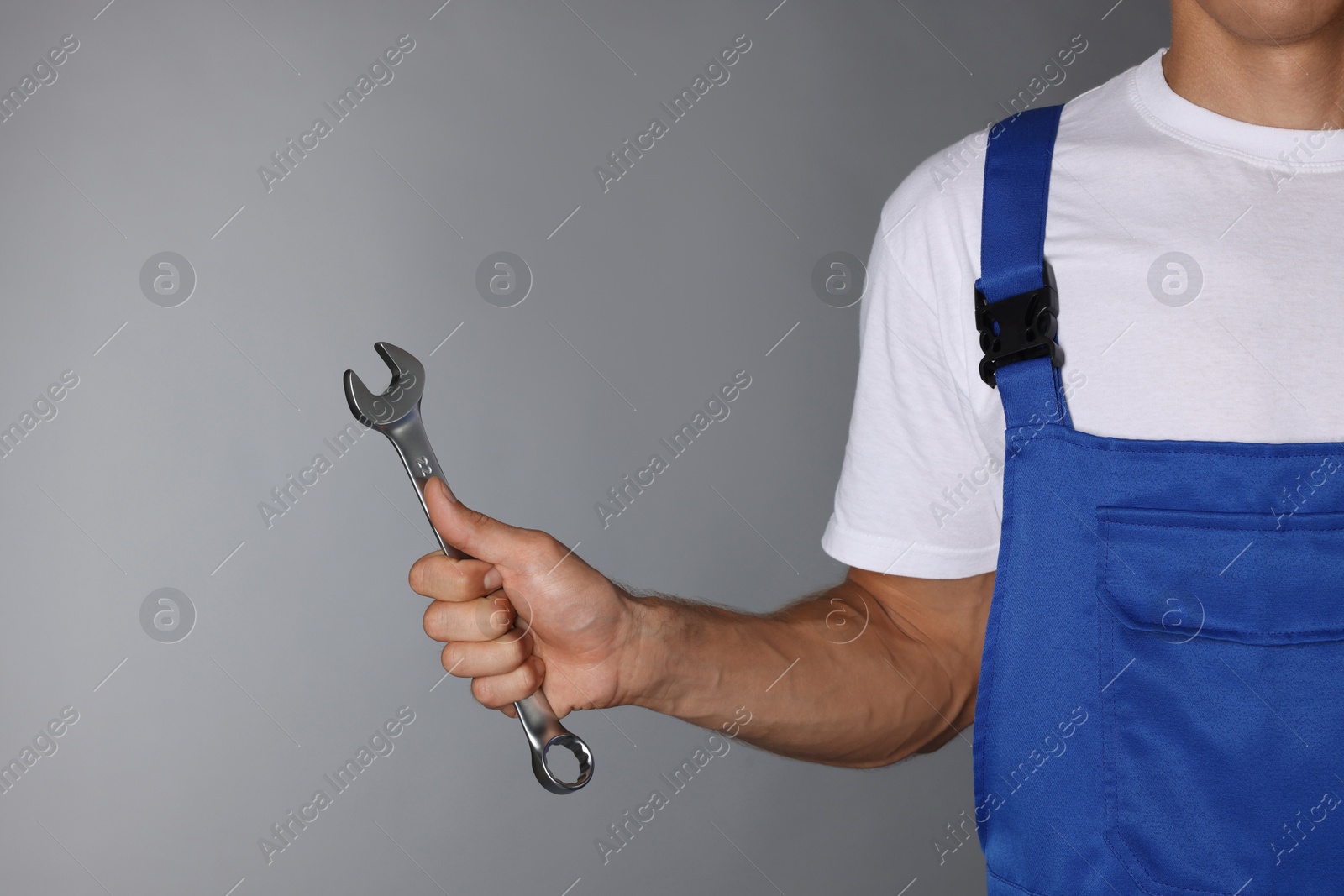 Photo of Auto mechanic with wrench on grey background, closeup