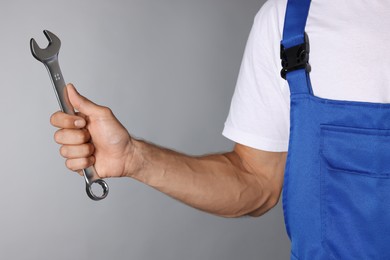 Photo of Auto mechanic with wrench on grey background, closeup