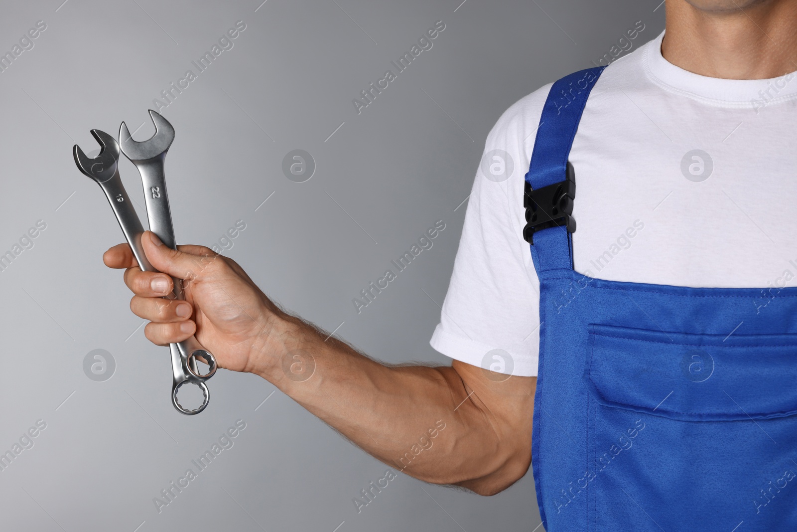 Photo of Auto mechanic with wrenches on grey background, closeup