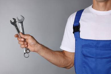 Photo of Auto mechanic with wrenches on grey background, closeup