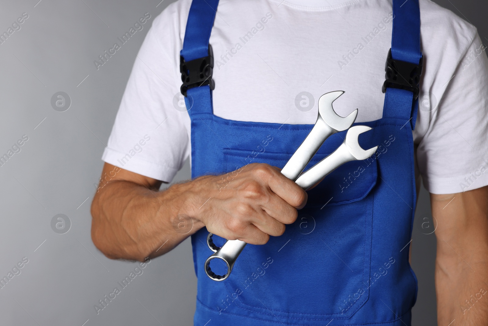 Photo of Auto mechanic with wrenches on grey background, closeup