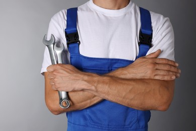 Photo of Auto mechanic with wrenches on grey background, closeup