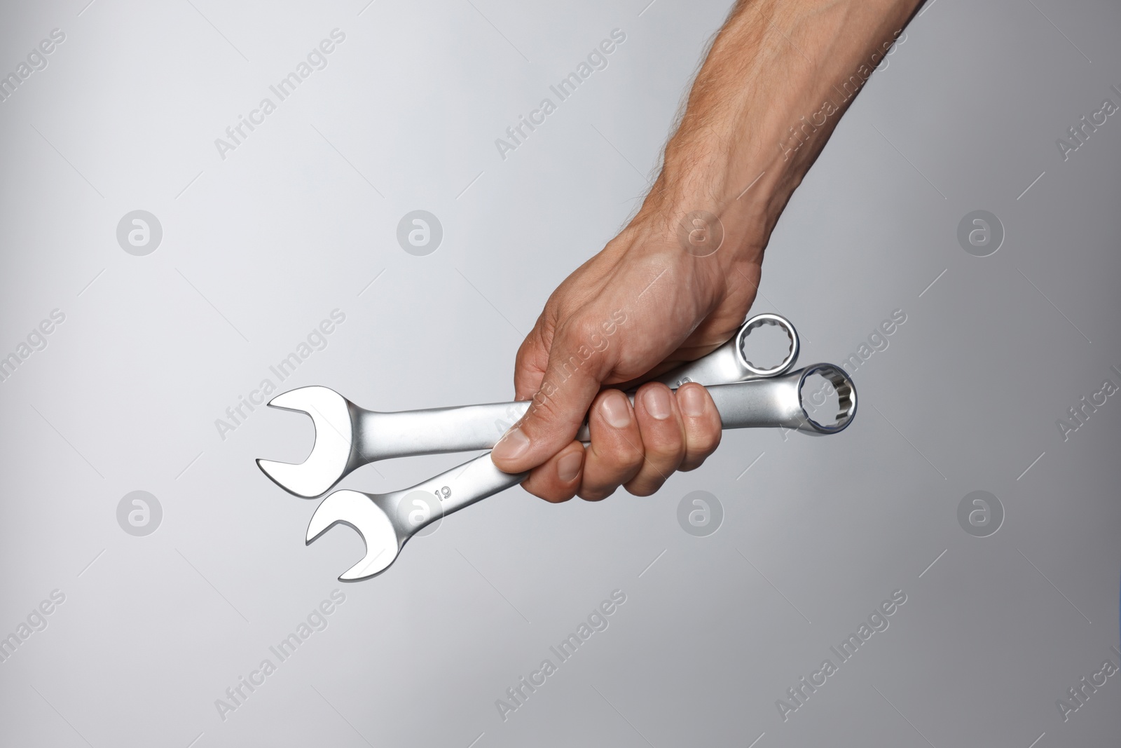 Photo of Auto mechanic with wrenches on grey background, closeup